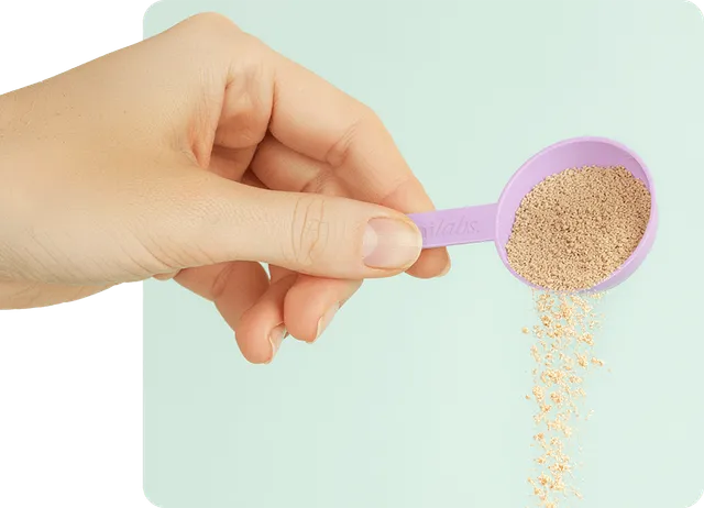 A hand holding a scoop of Bark Biotic powder