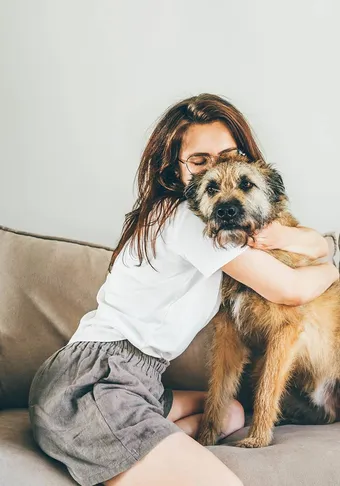 A woman hugging her dog on a sofa